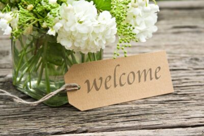 A welcome tag and a vase of flowers.